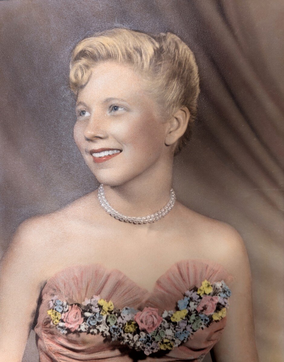 Hand-tinted portrait of Darlene as a young woman, blonde pinned curls and pearls.